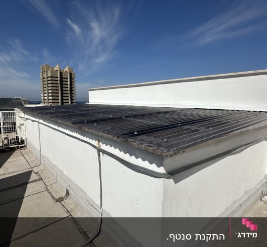 גג עם לוחות מתכת מחוררים ומעקה מתכת